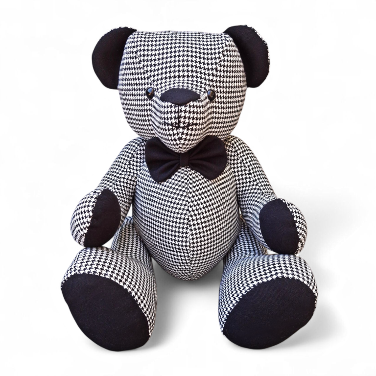 Gestreepte teddybeer met een zwarte strik en zwarte oortjes.